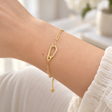Wrist wearing the gold Crystal Carabiner Link Bracelet with sparkling pavé carabiner detail and a cream knit sleeve