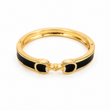 Gold bracelet with black accents on a white background