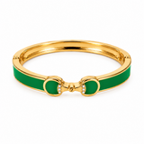 Gold bracelet with green enamel accents on a white background