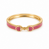 Gold bracelet with pink enamel horsebit on a white background