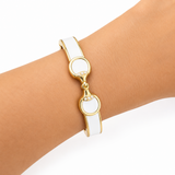 Gold and white bracelet on a wrist against a white background