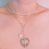 Layered gold-tone necklace featuring dual chain links and a vintage-inspired heart pendant centerpiece—offering a romantic, bold accent perfect for elevating any look.