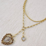 Layered gold-tone necklace featuring dual chain links and a vintage-inspired heart pendant centerpiece—offering a romantic, bold accent perfect for elevating any look.