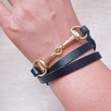 Equestrian-inspired double wrap bracelets featuring black and brown leather bands with horse bit accents in gold and silver tones.