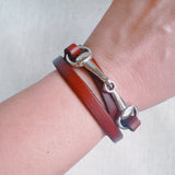 Equestrian-inspired double wrap bracelets featuring black and brown leather bands with horse bit accents in gold and silver tones.