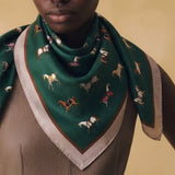 Person wearing a green scarf with horse pattern on a beige background