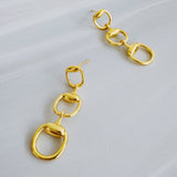Gold-tone drop earrings featuring three interlocking links inspired by classic horse bit and equestrian motifs. The polished finish and articulated structure create elegant movement and a refined, timeless statement style.
