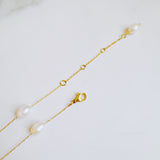 Gold bracelet with pearls on a light gray background