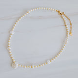 Gold-tone chain necklace featuring a mix of small polished pearls and irregular freshwater-style pearls, finished with an adjustable clasp closure.