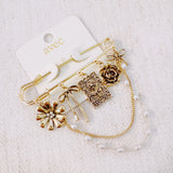 Gold-tone safety pin brooch adorned with floral and ribbon charms, delicate chain drapes, and pearl accents—offering a romantic, vintage-inspired accessory for bags, jackets, or scarves.