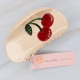 Playful cherry-themed hair claw clip featuring bright red cherries and green stems, adding a sweet and fruity flair to any hairstyle.
