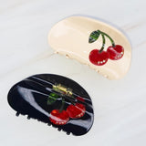 Playful cherry-themed hair claw clip featuring bright red cherries and green stems, adding a sweet and fruity flair to any hairstyle.