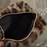 Compact travel bag with fuzzy leopard print texture, ideal for carrying makeup or daily essentials with style.