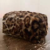 Compact travel bag with fuzzy leopard print texture, ideal for carrying makeup or daily essentials with style.