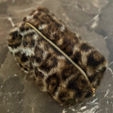 Compact travel bag with fuzzy leopard print texture, ideal for carrying makeup or daily essentials with style.