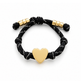 a black rope bracelet with gold heart charm on the white background
