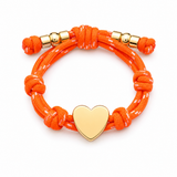 a orange rope bracelet with gold heart charm on the white background on white background