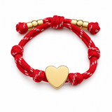a red rope bracelet with gold heart charm on the white background