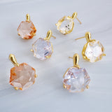 Artistic drop earrings featuring prism-cut gemstones framed by lustrous gold-tone metal. The angular yet fluid silhouette captures light beautifully, making each pair an elegant statement piece.