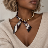 Model wearing the Golden Bead Scarf-Tie Necklace in Brown with a beige V-neck knit sweater