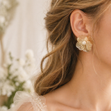 Close-up of a woman wearing a gold floral earring with a blurred background