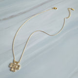 Elegant gold clover-shaped pendant encrusted with shimmering clear crystals. The Golden Clover Crystal Necklace features heart-shaped petals and a radiant gold finish, blending modern charm with timeless sparkle.