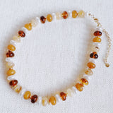 Beaded necklace featuring a blend of golden, amber, and brown-toned beads with subtle shimmer and natural variation, creating an earthy yet refined look.