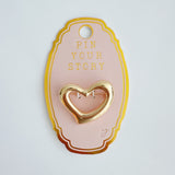 Shiny gold-tone heart-shaped brooch pin with fluid, sculptural lines and a modern artistic silhouette—perfect as a statement accent on jackets, scarves, or bags.