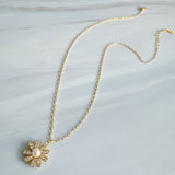 Gold-tone necklace featuring a daisy-inspired pendant with a luminous pearl center surrounded by sparkling crystal-studded petals. The design blends classic elegance with a fresh, feminine touch, perfect for layering or wearing solo.