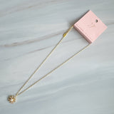 Gold-tone necklace featuring a daisy-inspired pendant with a luminous pearl center surrounded by sparkling crystal-studded petals. The design blends classic elegance with a fresh, feminine touch, perfect for layering or wearing solo.