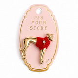 A gold-tone Italian Greyhound pin wearing a red knit sweater with a small rhinestone embellishment, attached to a light pink display card with gold trim and the text 'PIN YOUR STORY'.