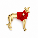A gold-tone Italian Greyhound dog brooch wearing a bright red yarn sweater with a small white crystal accent, shown on a plain white background.