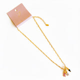 Close-up of a gold paperclip chain necklace featuring an eclectic mix of dangling gem-shaped charms in various cuts and colors, the stones clustered at the center.