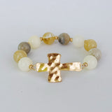 Bracelet with gold cross and multicolored beads on a light gray background