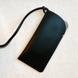 Glass case bag charm with an open-top design and strap attachment, perfect for hanging on your bag to hold glasses or other small essentials in style.