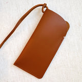 Glass case bag charm with an open-top design and strap attachment, perfect for hanging on your bag to hold glasses or other small essentials in style.