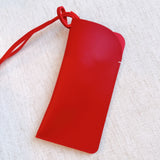 Glass case bag charm with an open-top design and strap attachment, perfect for hanging on your bag to hold glasses or other small essentials in style.