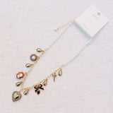 Gold-tone charm necklace featuring a mix of heart, bow, and angel motifs alongside vintage-style accents—blending sweet, romantic elements into a charming statement piece.