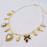 Gold-tone charm necklace featuring a mix of heart, bow, and angel motifs alongside vintage-style accents—blending sweet, romantic elements into a charming statement piece.