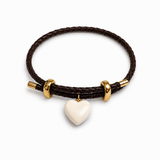 A dark brown braided cord bracelet with gold-toned metal accents and a small white heart-shaped charm, shown on a clean white background.