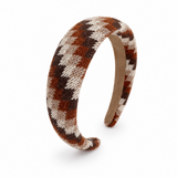 A knitted houndstooth headband in brown, beige, and black, displayed on a clean white background.