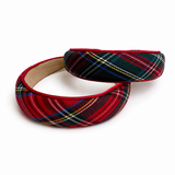 A pair of padded headbands with a red and black tartan plaid pattern, featuring thin white and yellow accent lines. One headband is laid flat to show the pattern and beige inner lining, while the other is rolled up.