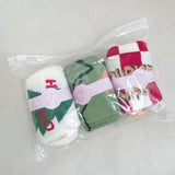 Set of three festive socks featuring holiday-themed designs, including Christmas colors and cheerful patterns, perfect for a cozy and jolly look.