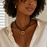 Woman wearing a necklace with a gold clasp in a neutral setting