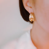 Statement earrings featuring bold interlocking loops in a polished gold-tone finish—offering a modern, sculptural look with standout appeal.