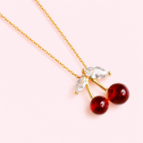 Necklace with cherry-shaped pendants on a light pink background