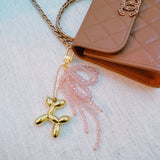 Pink & black beaded bow with a gold balloon dog charm – playful and chic design