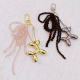 Pink & black beaded bow with a gold balloon dog charm – playful and chic design