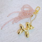 Pink & black beaded bow with a gold balloon dog charm – playful and chic design