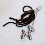 Pink & black beaded bow with a gold balloon dog charm – playful and chic design